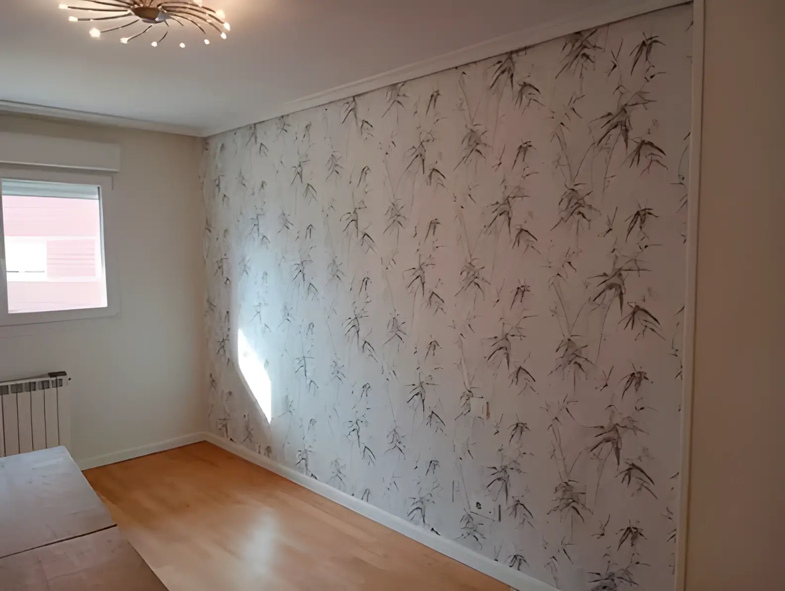 Los Pintores Badalona colocando papel pintado en pared de acento de habitación luminosa