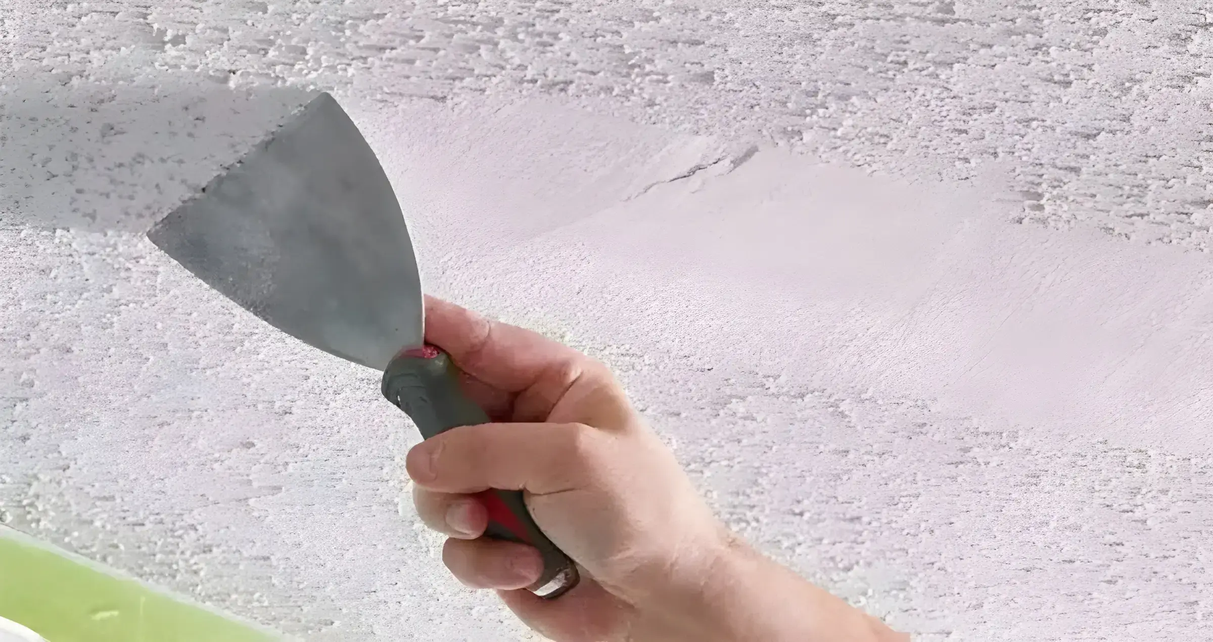 Los Pintores Badalona eliminando el gotelé con espátula para dejar la pared lisa